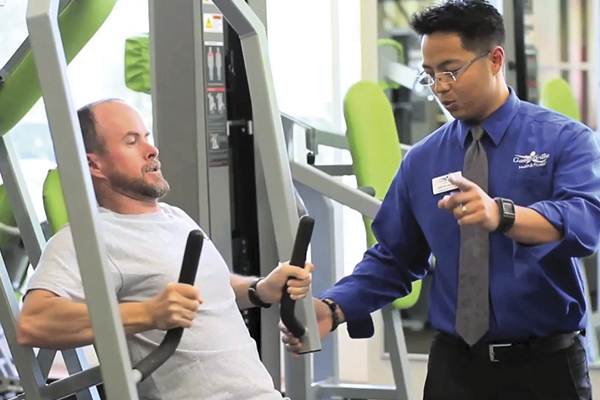 ghf staff helping a ghf member on the chest press machine at ghf tioga